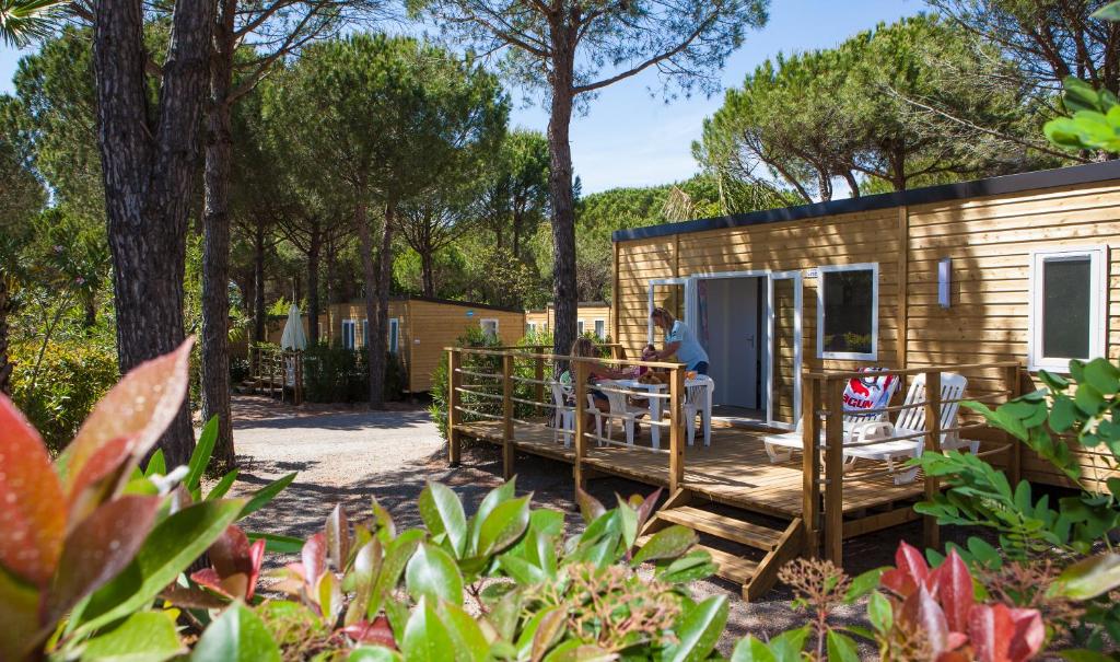 une personne assise sur la terrasse couverte d'une petite maison dans l'établissement Camping Resort La Baume La Palmeraie, à Fréjus