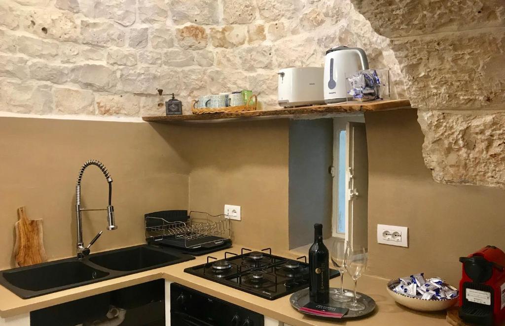 une cuisine avec un évier et une cuisinière four supérieur dans l'établissement Trulli Storie di Puglia - Private Pool, à Polignano a Mare