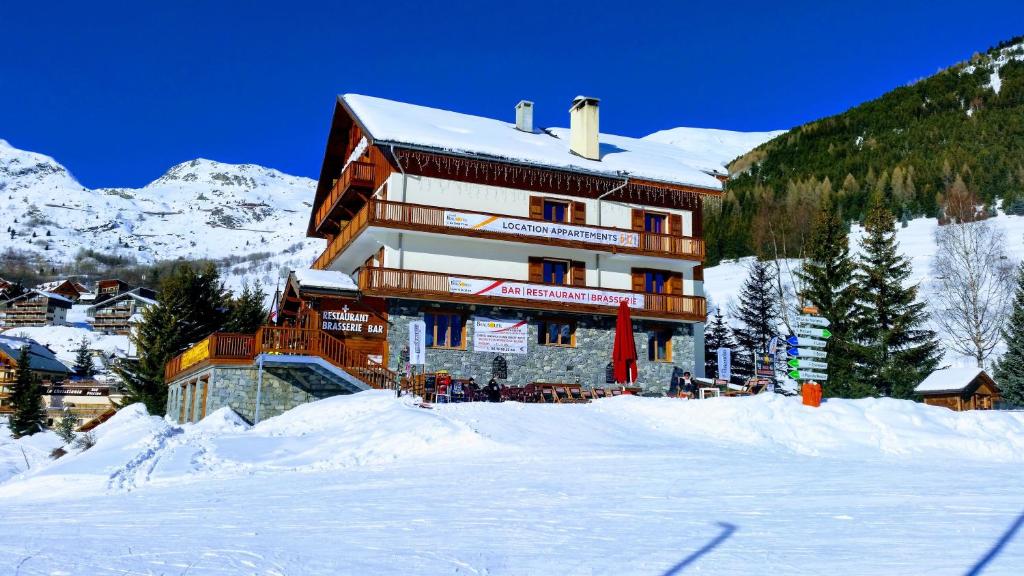 un grand bâtiment dans la neige devant une montagne dans l'établissement Chalet Beausoleil 4 étoiles - jacuzzi - au pied du Col de la Croix de Fer, à Saint-Sorlin-dʼArves