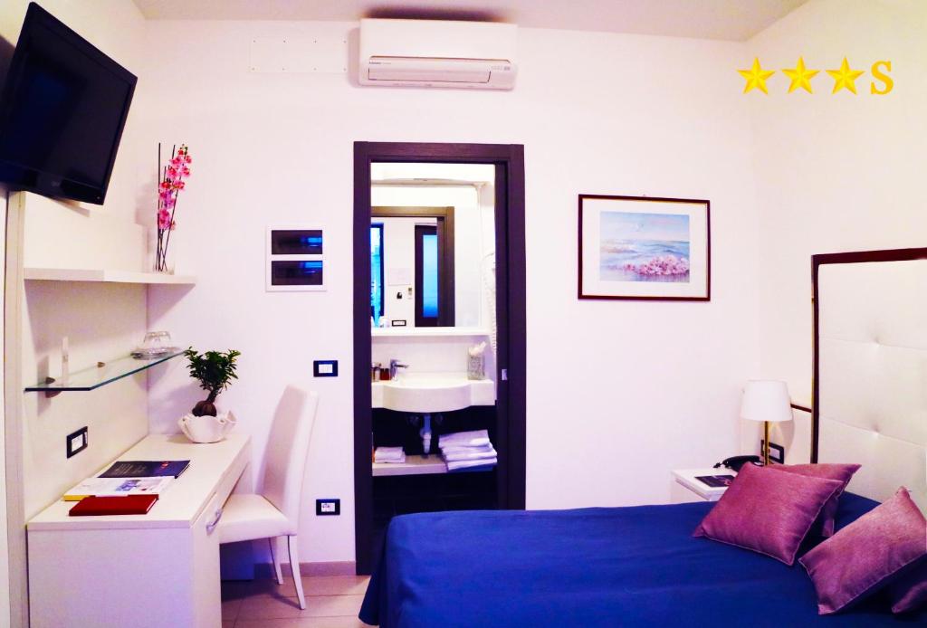 - une chambre avec un lit bleu et un lavabo dans l'établissement Hotel Rossini 4S, à Lignano Sabbiadoro