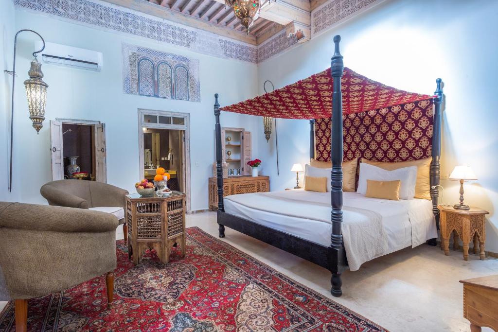 une chambre avec un lit à baldaquin et une chaise dans l'établissement Riad Azoulay, à Marrakech