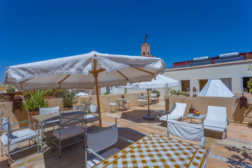 un patio avec tables, chaises et un parasol dans l'établissement Riad Azoulay, à Marrakech
