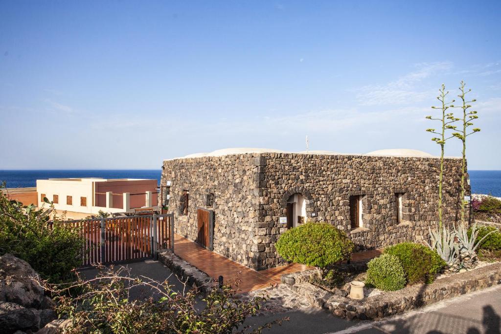 une maison en pierre avec l'océan en arrière-plan dans l'établissement Pantelleria Resort, à Pantelleria