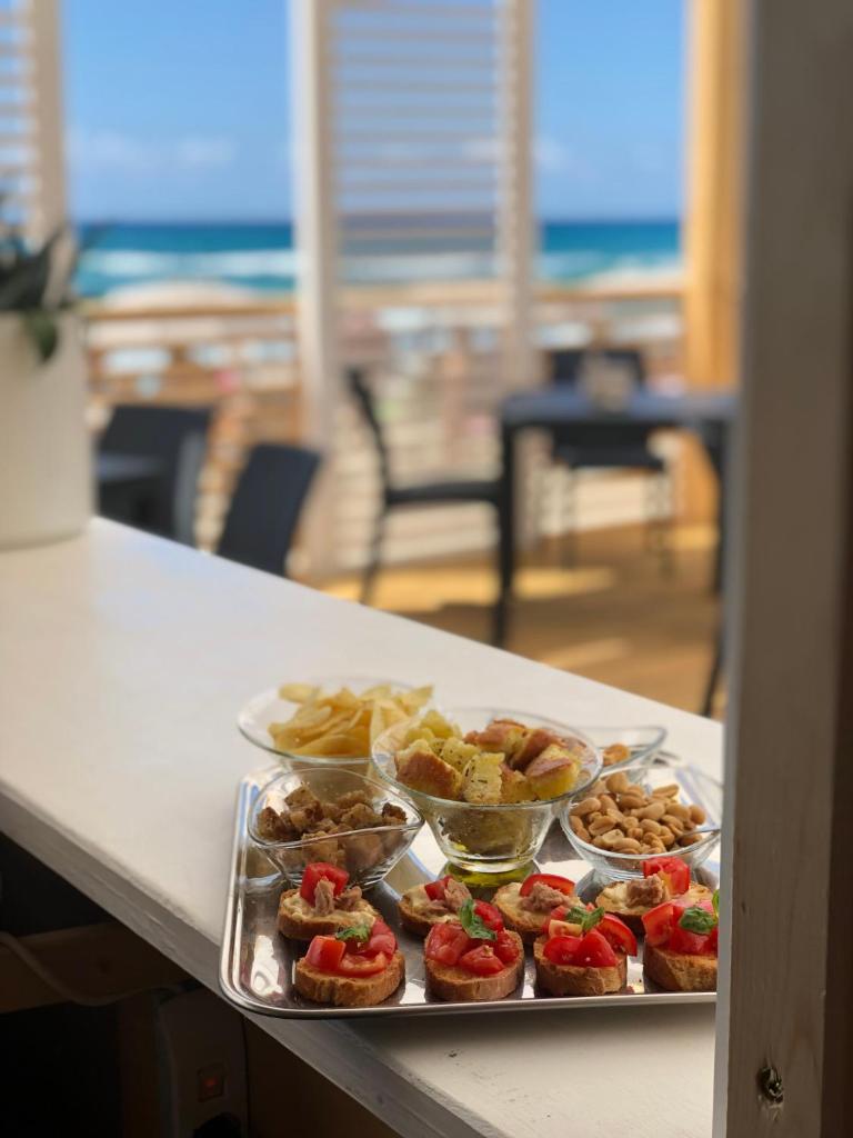- une table avec plusieurs plateaux de nourriture sur une table avec la plage dans l'établissement Residence Le Palme - Appartamenti sul mare - Spiaggia tra Palinuro e Caprioli, à Pisciotta