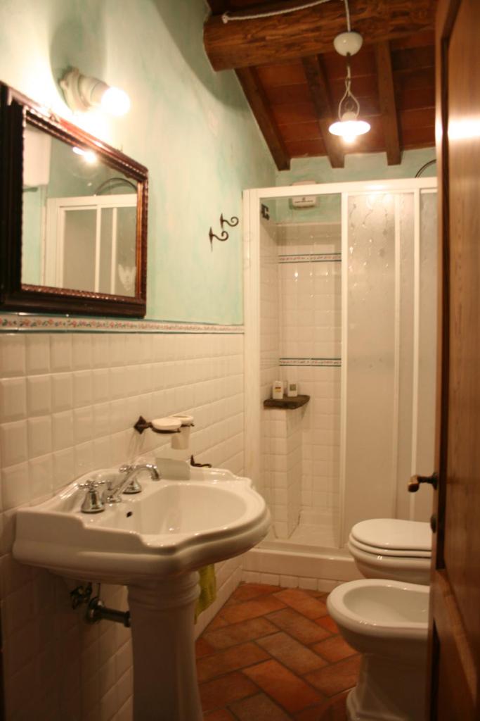 une salle de bain avec un lavabo, des toilettes et un miroir dans l'établissement Torre Di Vignale, à Palazzo del Pero