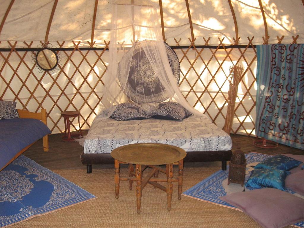 - une chambre avec un lit et une table dans une yourte dans l'établissement Camping Mille Étoiles, à Labastide-de-Virac
