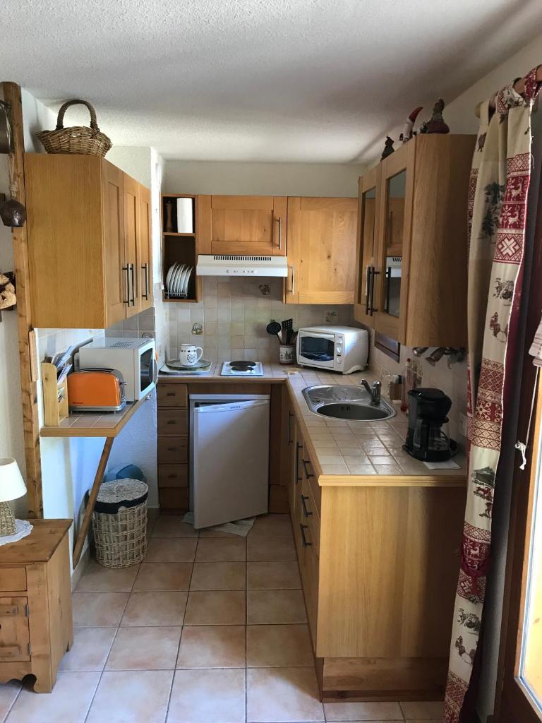 Elle comprend une petite cuisine avec des placards en bois et un évier. dans l'établissement Le Croisse Baulet, à La Giettaz