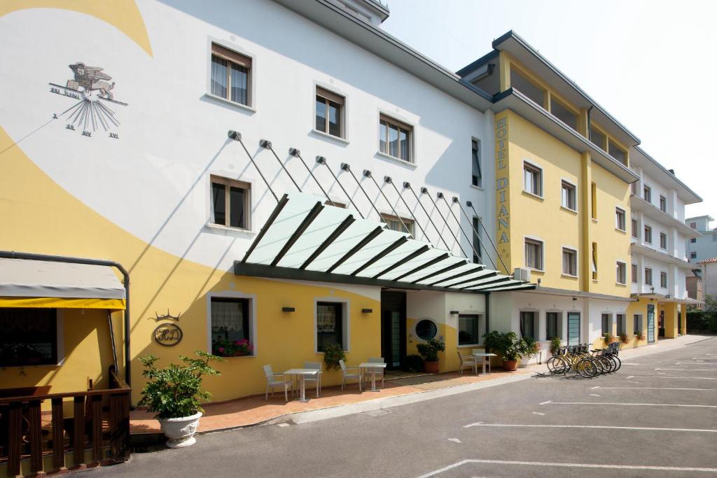 un bâtiment jaune et blanc avec des tables et des chaises dans l'établissement Hotel Diana, à Lido di Jesolo