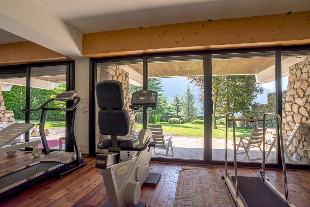 - une salle de sport avec un tapis de course et une grande fenêtre dans l'établissement Villa Mazzucco, à Ponte nellʼAlpi