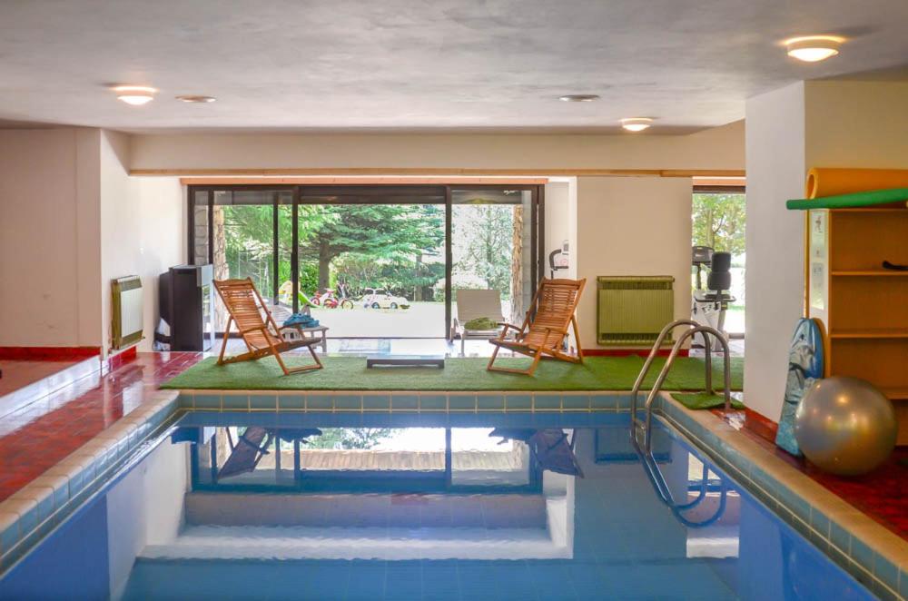 une piscine avec deux chaises et une table dans l'établissement Villa Mazzucco, à Ponte nellʼAlpi