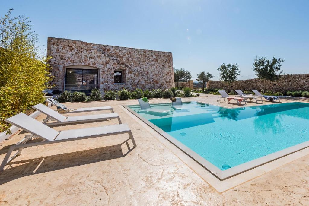 une piscine extérieure avec des chaises longues et une maison dans l'établissement Villa Arja, à Corsano