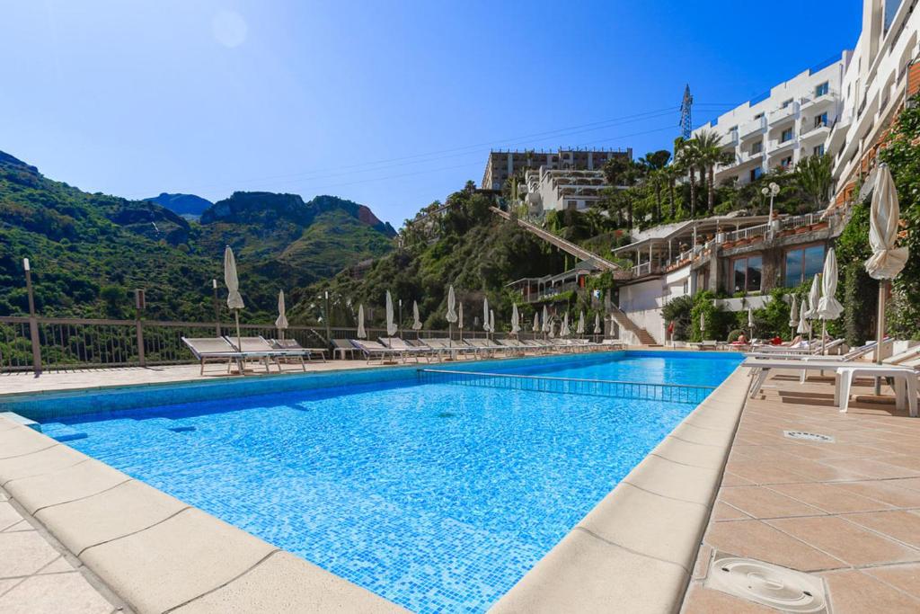 une piscine avec des montagnes en arrière-plan dans l'établissement Hotel Antares, à Letojanni
