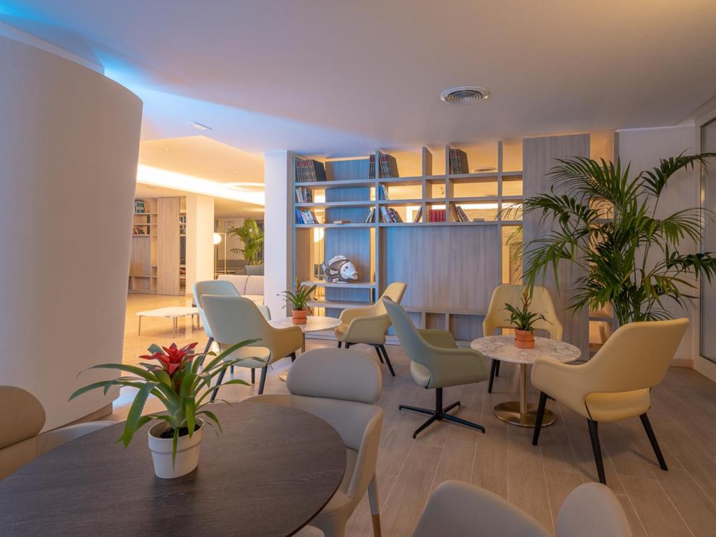 une salle d'attente avec des chaises, des tables et des plantes dans l'établissement Hotel Antares, à Letojanni