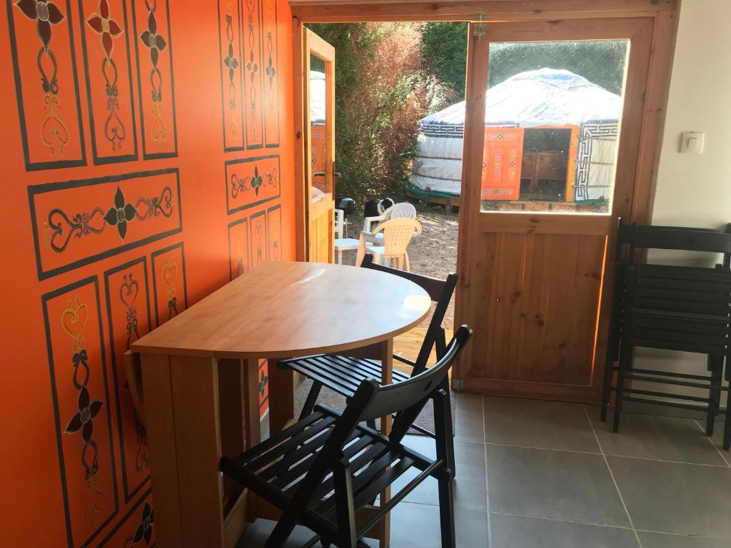 - une table et des chaises en bois dans une chambre avec fenêtre dans l'établissement yourte Coeur de Combray, à Ernes