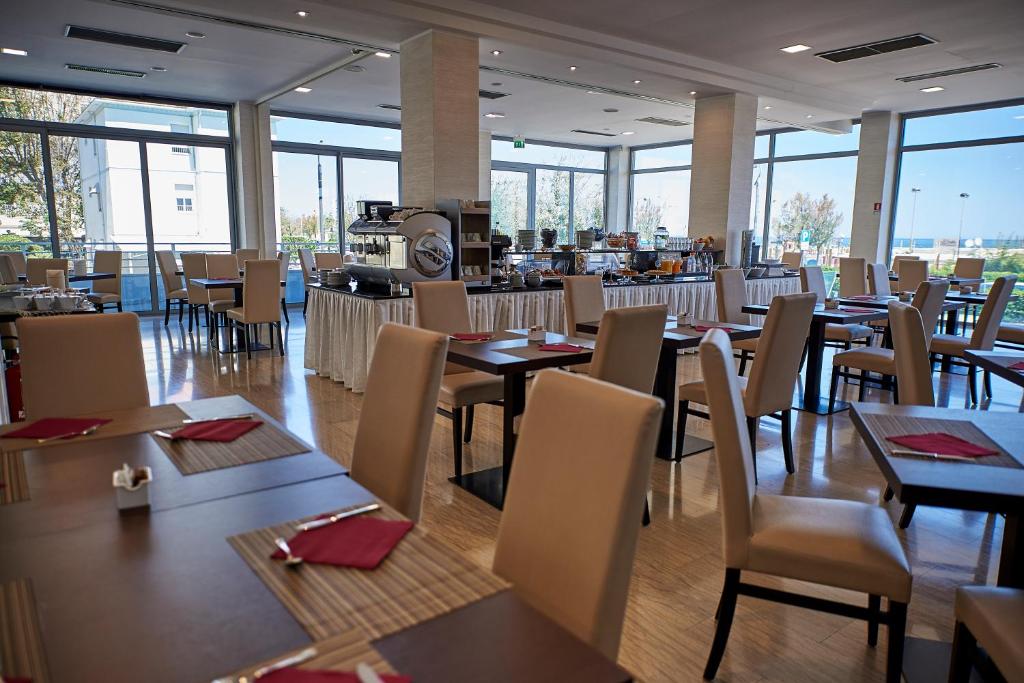 une salle à manger avec tables, chaises et fenêtres dans l'établissement Alisei Palace Hotel, à Rimini