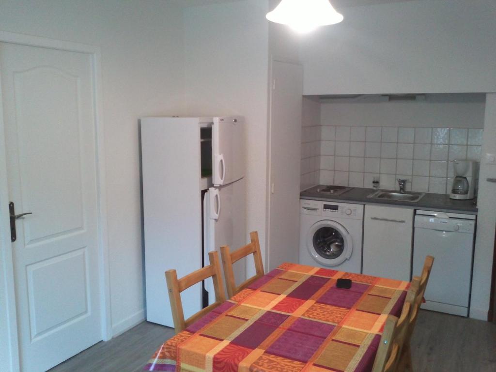 une cuisine avec une table et un réfrigérateur blanc dans l'établissement T2 250m du centre ville AX-LES-THERMES, à Ax-les-Thermes