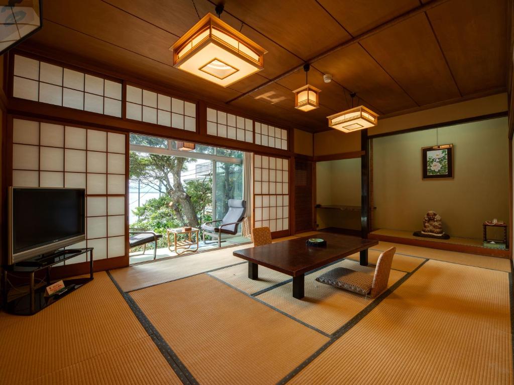 un salon avec une table et une télévision dans l'établissement Iwamotoro, à Fujisawa