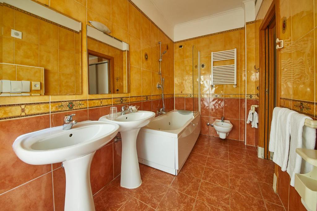 une salle de bain avec deux lavabos et une baignoire et des toilettes dans l'établissement Hotel Vienna Ostenda e Ristorante il Danubio, à Rimini