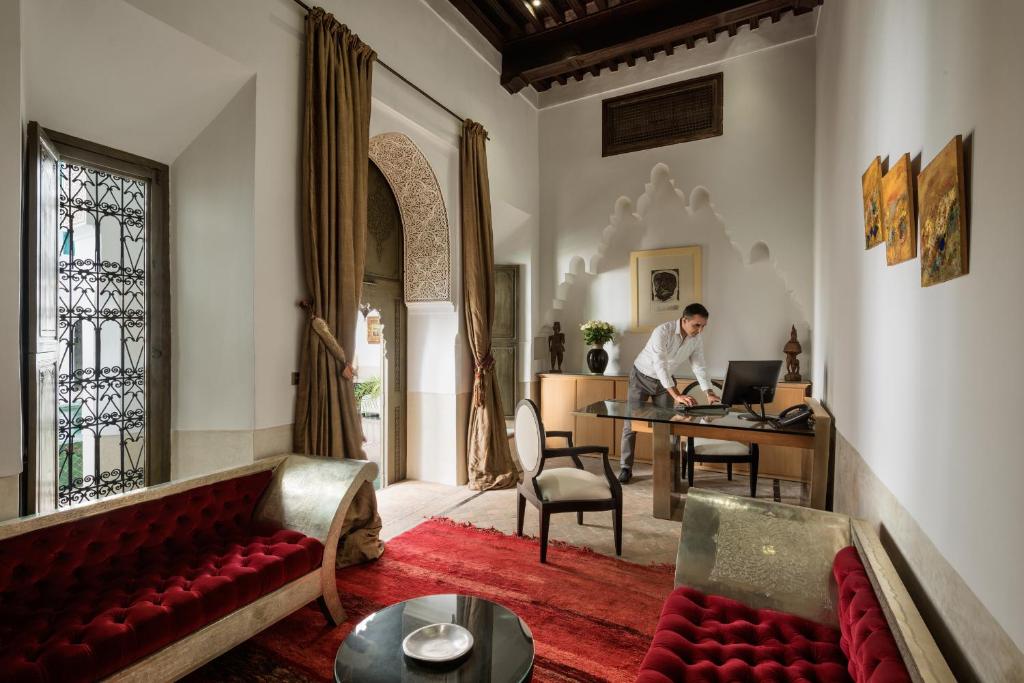 un homme assis à un bureau avec un ordinateur portable dans le salon dans l'établissement Le Farnatchi, à Marrakech
