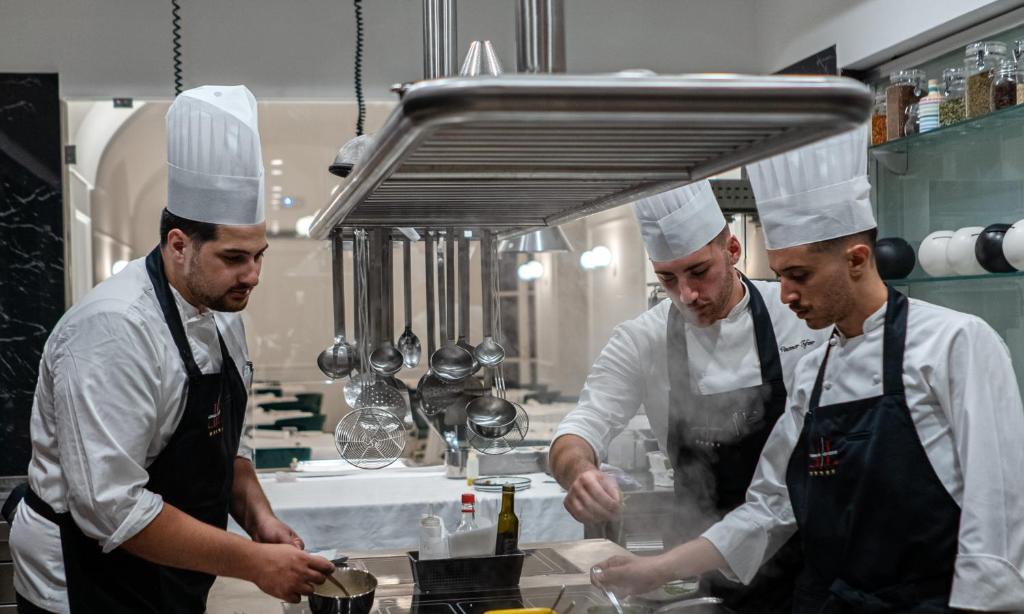 trois chefs debout dans une cuisine préparant des plats dans l'établissement Hotel Lorelei Londres, à Sorrente 90 autres photos