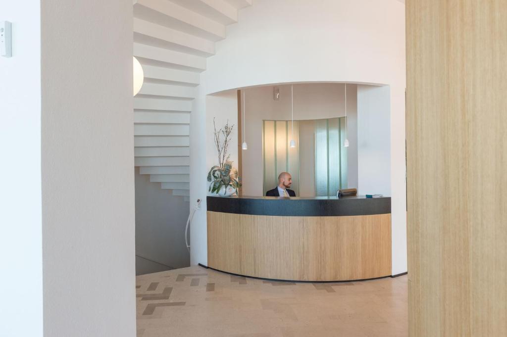 un homme assis à un comptoir d'accueil dans un hall dans l'établissement Hotel Torremaura, à Milano Marittima
