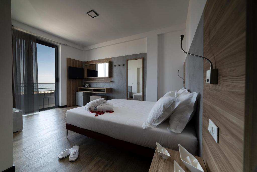 - une chambre avec un lit doté de draps blancs et un balcon dans l'établissement Alisei Palace Hotel, à Rimini