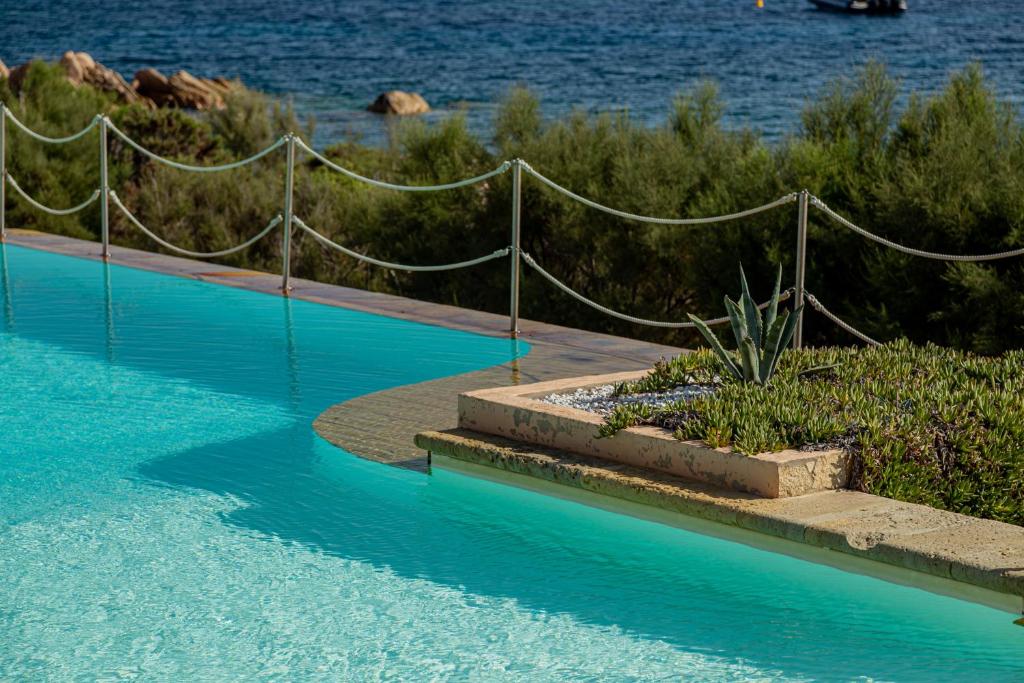 une piscine d'eau bleue et une clôture dans l'établissement Hotel Cala Lunga, à La Maddalena