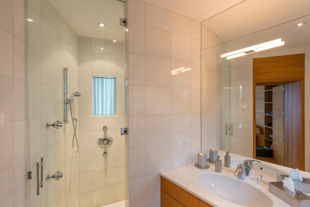 une salle de bain avec un lavabo, une douche et un miroir dans l'établissement Turm Chalet, à Laces