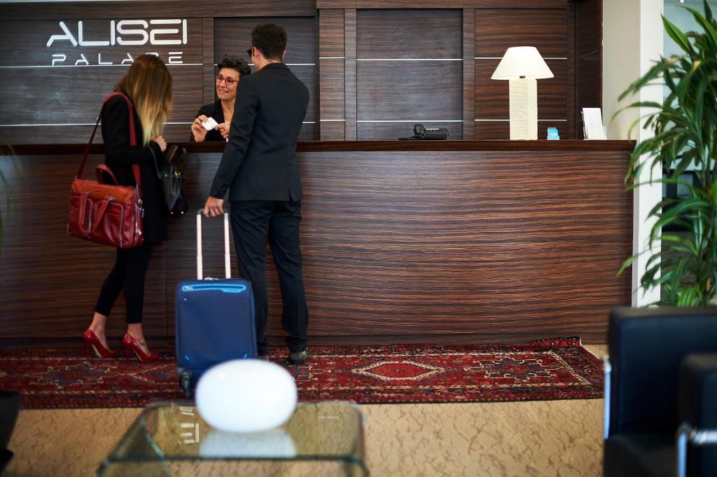 un homme et une femme debout au comptoir d'un hôtel avec leurs bagages dans l'établissement Alisei Palace Hotel, à Rimini 45 autres photos