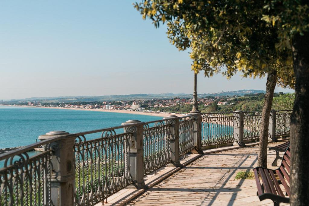 un banc sur une passerelle à côté d'une plage dans l'établissement NUMA HOTEL, à Numana