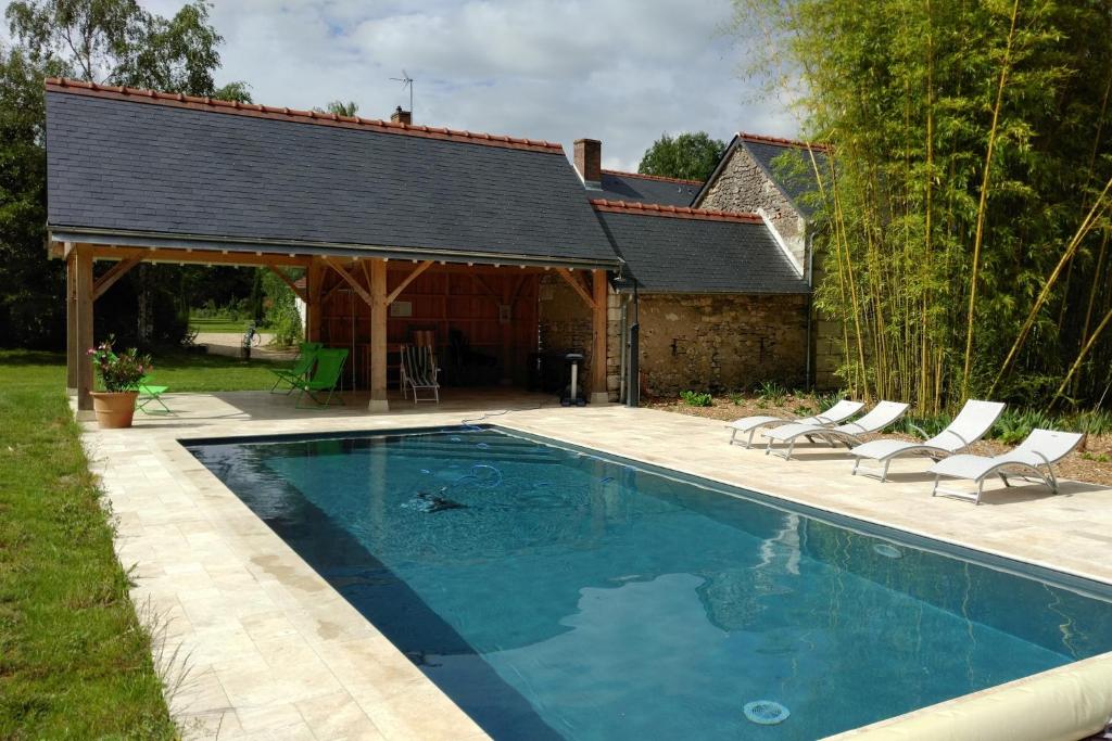 une piscine avec des chaises et une maison dans l'établissement Le gîte de l'Hermine - La Blinerie, à Sambin