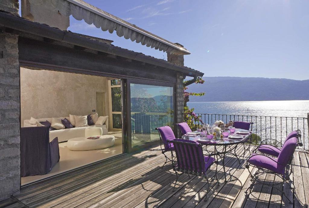 un patio avec des chaises violettes et une table sur une terrasse dans l'établissement Villa Rachele: stunning luxury villa in centre Gargnano with private pool and breathtaking views, à Gargnano