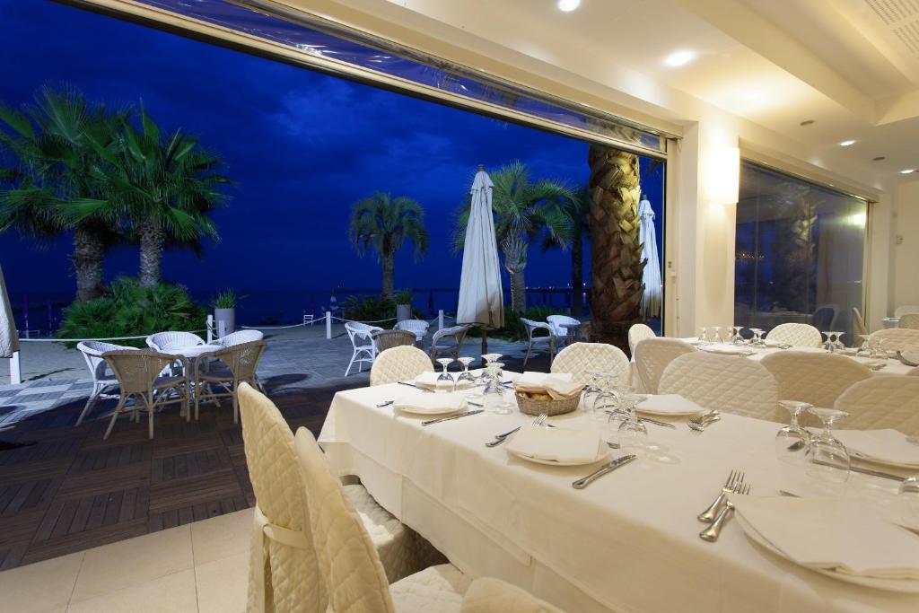un restaurant avec des tables et des chaises blanches et une grande fenêtre dans l'établissement Hotel Il Timone, à Porto San Giorgio