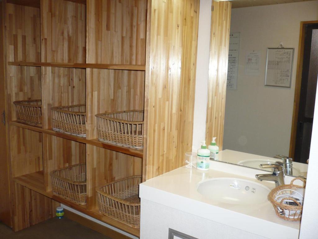 La salle de bains est pourvue d'un lavabo et d'un mur en bois. dans l'établissement Oyado Nozawaya, à Nozawa Onsen