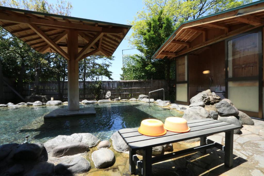- une piscine avec une table de pique-nique avec deux chapeaux dans l'établissement Minshuku Miyama, à Yamanouchi