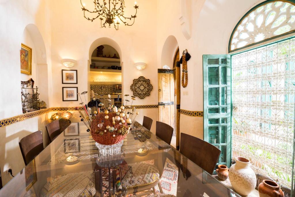 une salle à manger avec une table en verre et un lustre dans l'établissement Dar Kleta, à Marrakech