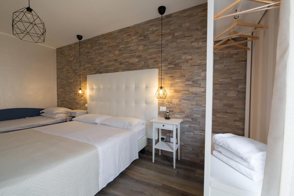 une chambre avec deux lits et un mur de briques dans l'établissement Hotel Blue Marine, à Lignano Sabbiadoro