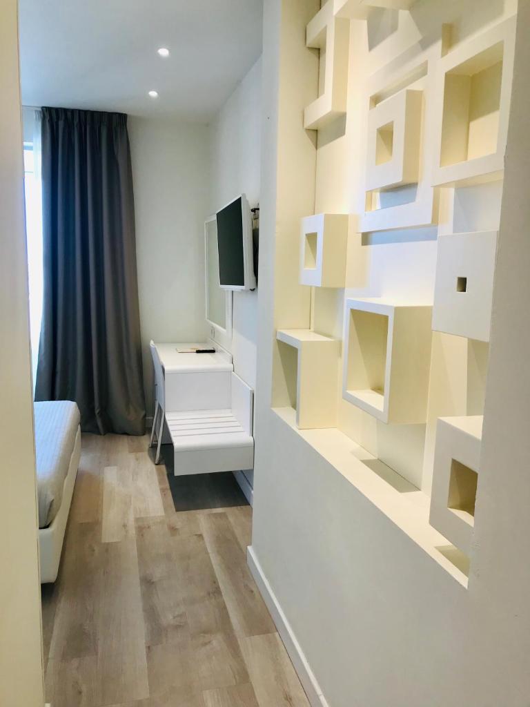 une chambre avec un lit, une télévision et des étagères dans l'établissement Hotel Aristeo, à Rimini