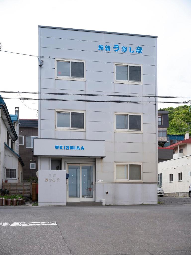 un bâtiment blanc avec un panneau dessus dans l'établissement Shimanoyado Rebunshiri, à Rebun