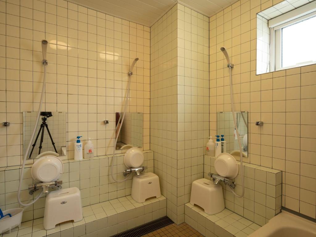 La salle de bains est pourvue de 2 urinoirs blancs et d'une fenêtre. dans l'établissement Shimanoyado Rebunshiri, à Rebun