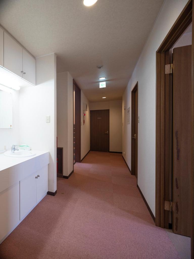 une chambre vide avec un couloir avec un lavabo et un couloir dans l'établissement Shimanoyado Rebunshiri, à Rebun