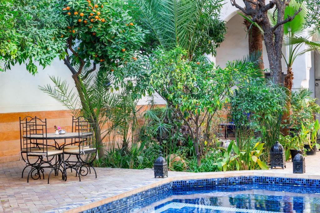 - une table et des chaises à côté de la piscine dans l'établissement Riad Laila, à Marrakech