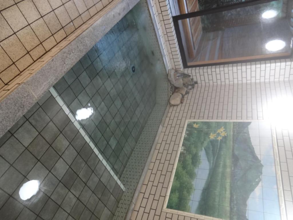 La salle de bains est pourvue d'une douche en verre et d'une fenêtre. dans l'établissement Mizubasho no Yado Higashi, à Katashina
