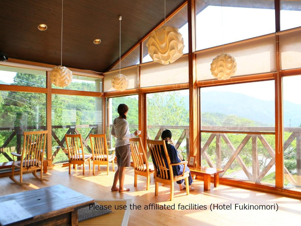2 personnes debout à une table dans une chambre avec fenêtres dans l'établissement Tokonamiso, à Nagiso 7 autres photos