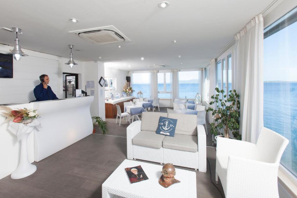 une femme debout dans un salon avec des chaises et des tables dans l'établissement Hotel La Caletta, à Porto Santo Stefano