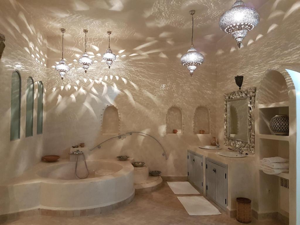 La salle de bains est pourvue d'une baignoire, de 2 lavabos et de lustres. dans l'établissement Palais Villa Talaa Resort, à Taroudant