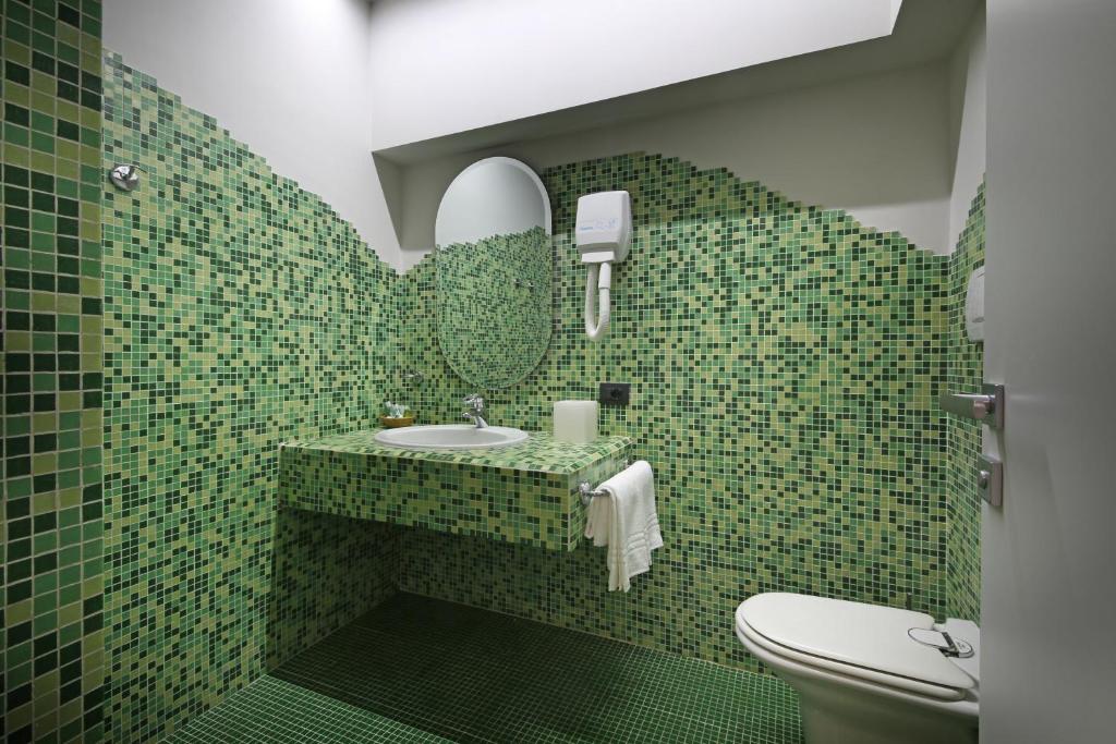 une salle de bain carrelée verte avec un lavabo et des toilettes dans l'établissement Hotel Salò du Parc, à Salò