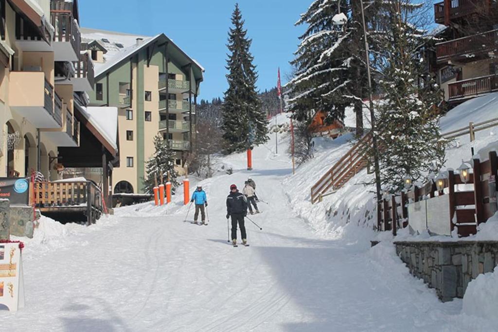 un groupe de personnes skier sur une piste enneigée dans l'établissement Les Myrtilles, à Oz