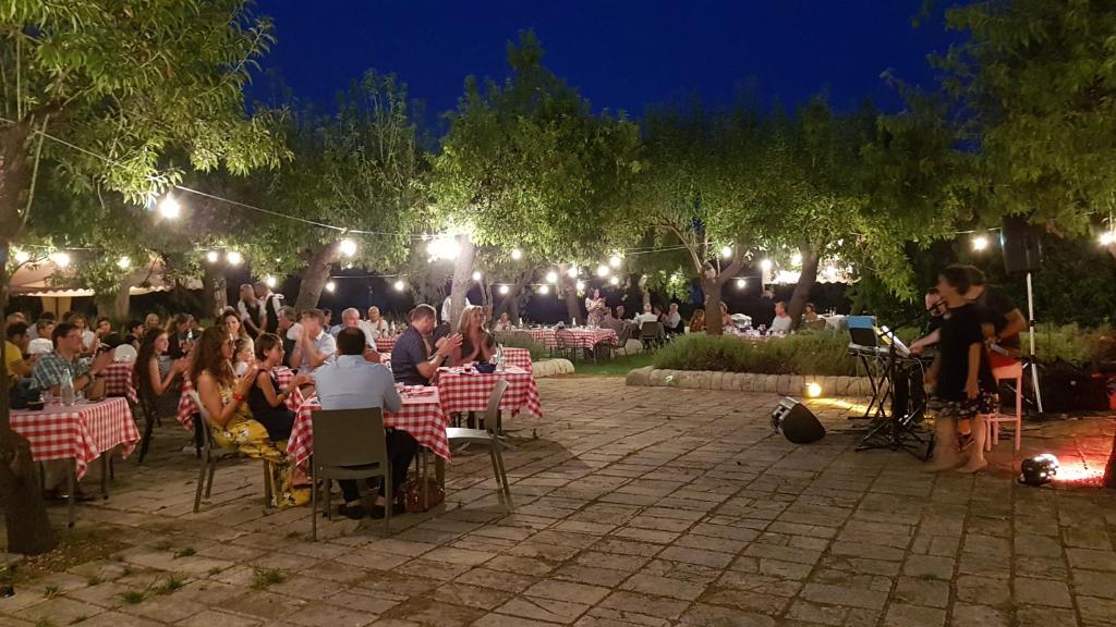 une foule de personnes assises à des tables dans un jardin la nuit dans l'établissement Hotel La Corte Del Sole, à Noto 156 autres photos
