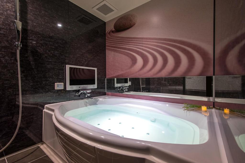 une baignoire dans une salle de bain avec une télévision dans l'établissement HOTEL ZEN HIRANO (Adult Only), à Osaka